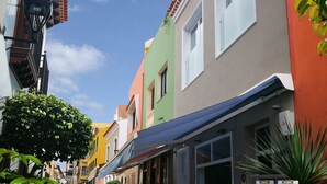 Eine schmale Straße, gesäumt von farbenfrohen Gebäuden, von denen einige Geschäfte und Sonnenschirme haben.