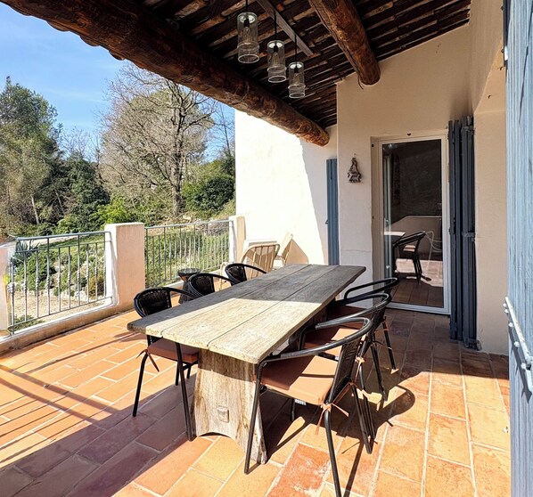 An outdoor patio with a wooden table and chairs, a railing, and a view of trees. - Aix-en-Provence, provencal family house (Éguilles)