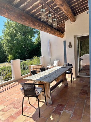 An outdoor patio with a wooden table and chairs, a pergola with hanging lights, and a view of greenery. - Aix-en-Provence, provencal family house (Éguilles)