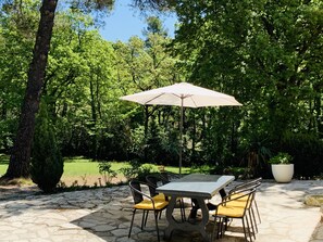 An outdoor patio with a stone table and chairs, surrounded by lush greenery and trees. - Aix-en-Provence, provencal family house (Éguilles)