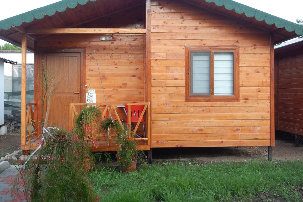 Una cabana de fusta amb un porxo, una porta i una finestra.