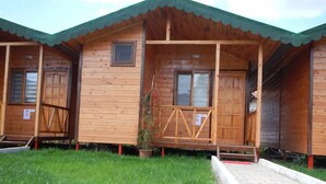 A wooden cabin with a porch, a small window, and a door.
