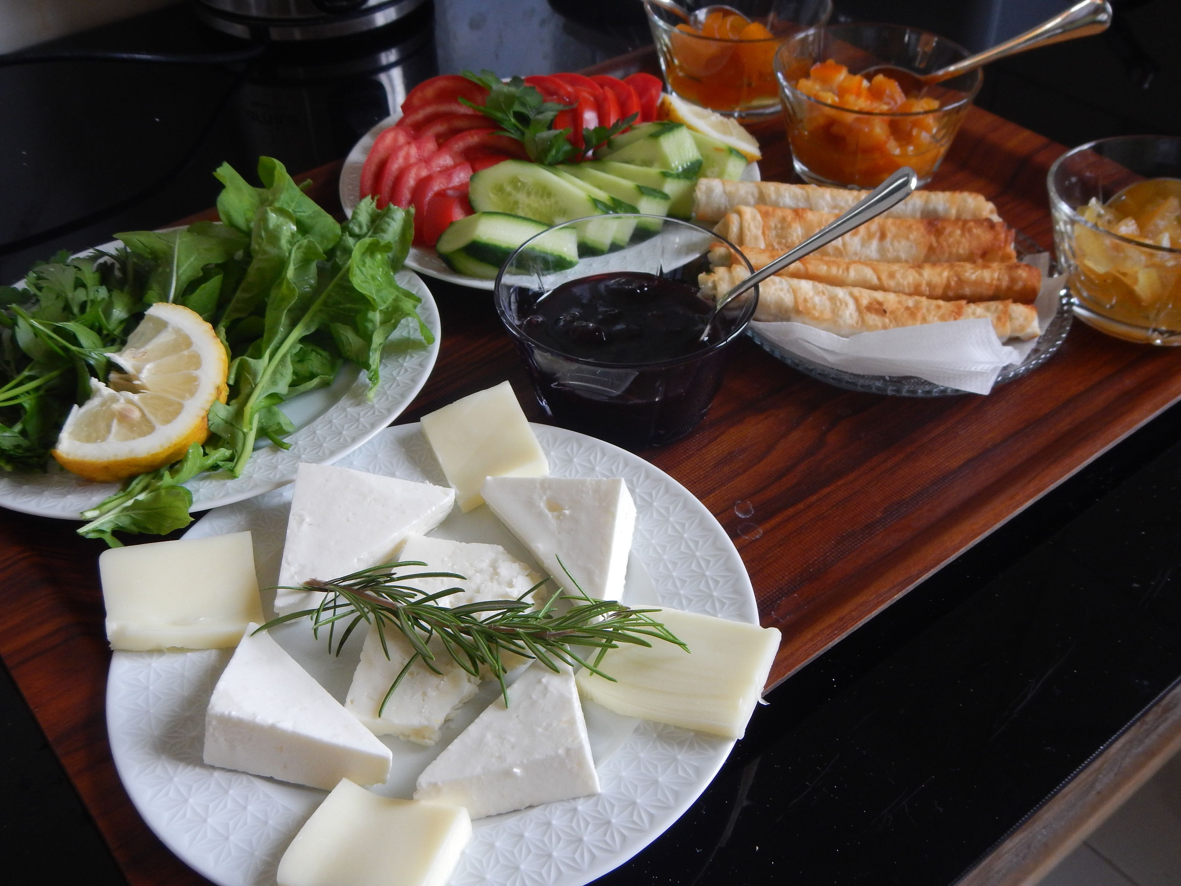 Una mesa con diversos alimentos, como queso, verduras y pan.