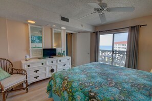 Quarto com cama grande, penteadeira, televisão e vista para o mar.