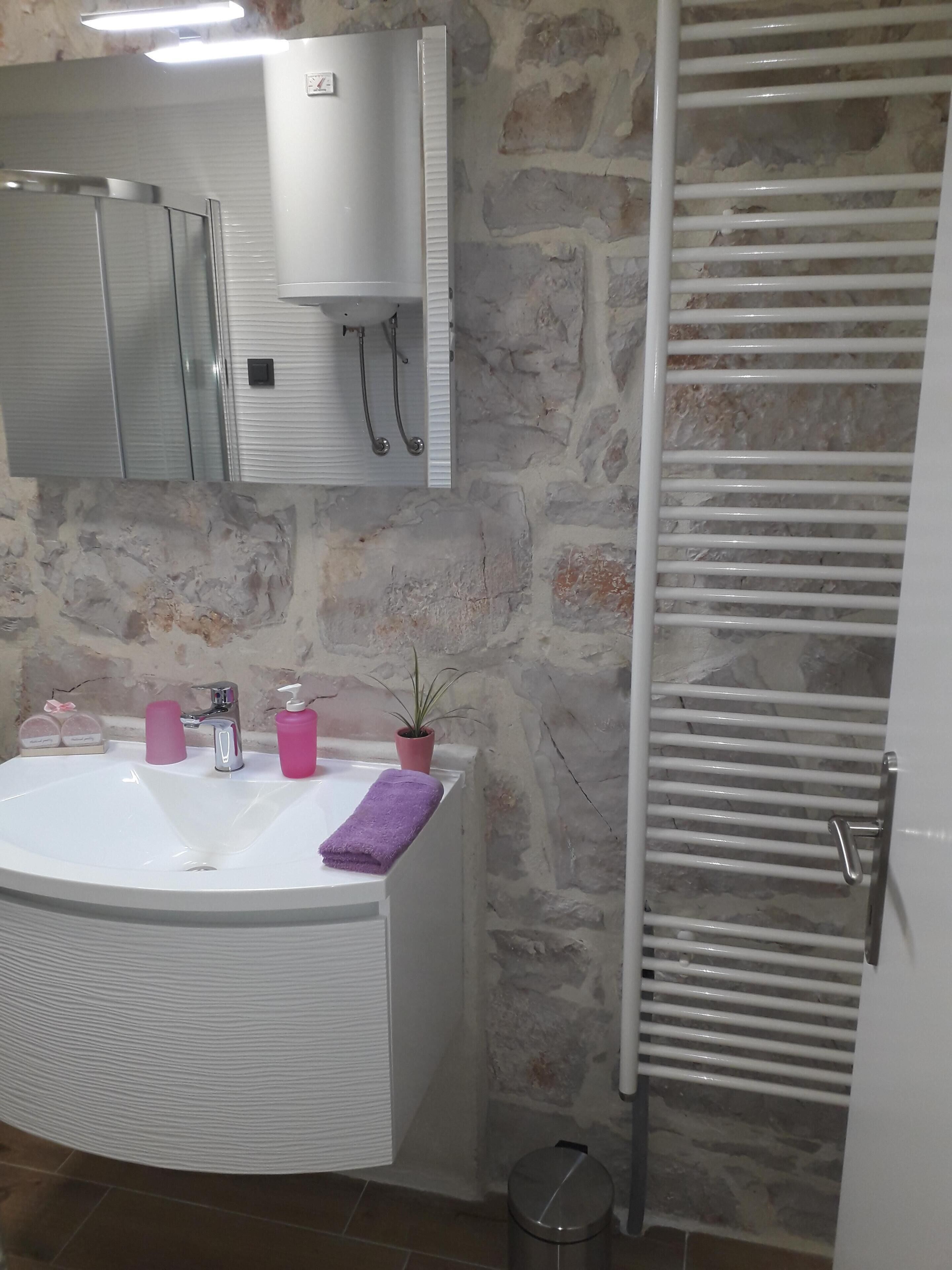 A bathroom with a white sink, a mirror, a towel, and a potted plant.
