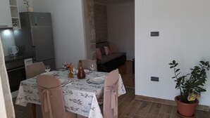 Un comedor con una mesa preparada para cuatro, un refrigerador y una planta en maceta.
