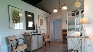 A spacious room with a large mirror, a wooden cabinet, a dining table with chairs, and a decorative lamp. - Corfu Golf Countryhouse (Corfu)
