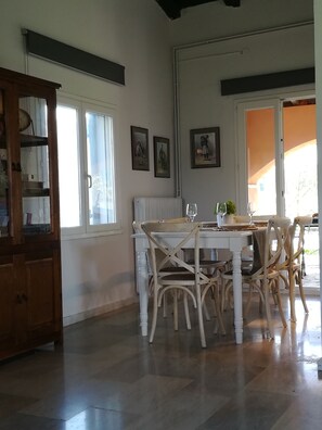 A dining area with a white table and chairs, a radiator, and framed pictures on the wall.