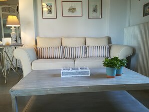 A living room with a sofa, striped cushions, a coffee table, a lamp, and framed artwork on the wall.
