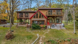 A cabin with a deck, a covered porch, and a small outdoor seating area. - River Time Cabin -riverfront, wifi, screen porch, 3 king beds, view, wood stove (Great Cacapon)
