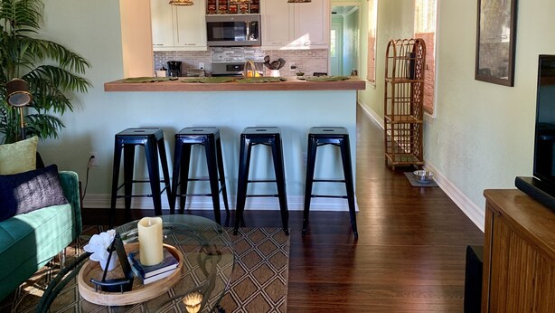 A modern kitchen with white cabinets, a central island, and pendant lighting. - Stylish 2 BED, 2 BATH Shotgun-style house near beach! (Galveston)