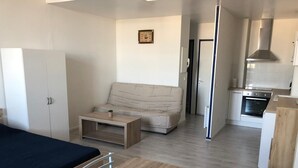 Un apartamento moderno con kitchenette, sofá, mesa de comedor y cama.