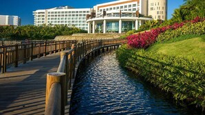 A waterfront hotel with a wooden boardwalk, a circular building, and lush greenery. - Vidanta, 5 Diamond Resort 1Br 1 1/2 Ba + golf 2 for 1 massages (Nuevo Vallarta)