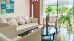 A living room with a sofa set, a coffee table, and a door leading to a balcony with plants. - La Papaya- Luxury Condo-complete apartment in PDC (Playa del Carmen)