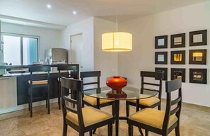 A modern dining area with a round glass table, black chairs, and a red vase centerpiece.