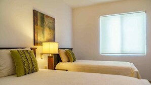 A hotel room with two beds, a nightstand with a lamp, a painting on the wall, and a window providing natural light. - La Papaya- Luxury Condo-complete apartment in PDC (Playa del Carmen)