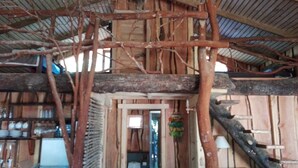 Une structure rustique en bois, dotée d’un plafond haut et de poutres apparentes.
