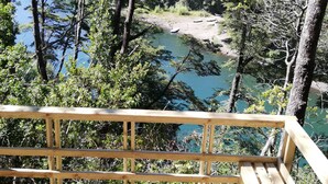 Une terrasse en bois donnant sur un lac, lui-même entouré d’arbres.