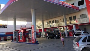 Una estación de servicio llamada Posto Lunara con varias bombas de combustible, un pequeño quiosco y una escalera que lleva a un nivel superior.