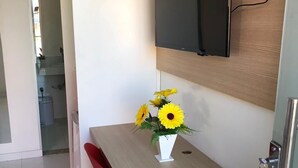 Una cocina moderna con televisor integrado, una mesa pequeña con un florero de girasoles y una silla roja.