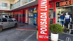 Fachada con un letrero rojo que dice "POUSADA LUNARA" y un número de contacto.