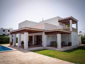 A modern two-story house with a covered patio, a swimming pool, and a well-maintained lawn.