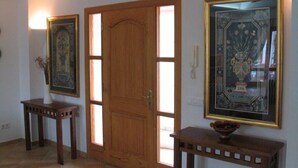 A hallway with a wooden door, two small tables, and framed artwork on the walls. - Spacious Villa in Cala D'or Marina  (Cala D'or)