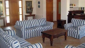 A living room with striped sofas, a wooden coffee table, and a tiled floor. - Spacious Villa in Cala D'or Marina  (Cala D'or)
