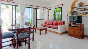 A living room with a sofa, TV, and dining area with chairs and a table.