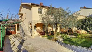 A two-story house with a covered patio and a stone staircase leading to the entrance.