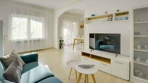 A modern living room with a teal sofa, a flat-screen TV, and a white entertainment unit.
