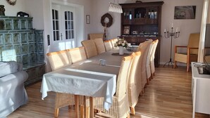 A dining area with a long table, wicker chairs, and a cabinet with glass doors.