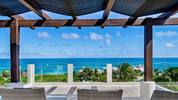 A covered outdoor seating area with wicker chairs and a view of the ocean.