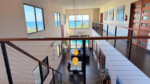 A spacious interior with large windows offering ocean views, a modern staircase, and a dining area with a view.