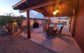 Un patio exterior con piscina, mobiliario y ventilador de techo.