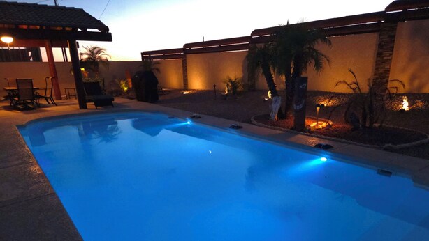 A swimming pool with a tiled deck, a covered seating area, and a wall with decorative lighting. - Lake Havasu Pool Garage/Boat Parking 5Min Riviera Marina London Bridge & DT (Lake Havasu City)