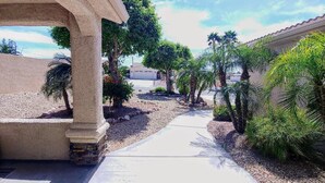 A pathway flanked by palm trees and a building with a stone facade. - Lake Havasu Pool Garage/Boat Parking 5Min Riviera Marina London Bridge & DT (Lake Havasu City)