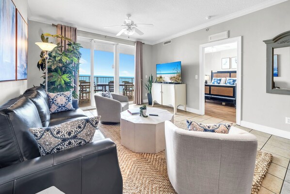 A modern living room with a leather sofa, a round coffee table, and a view of the balcony.