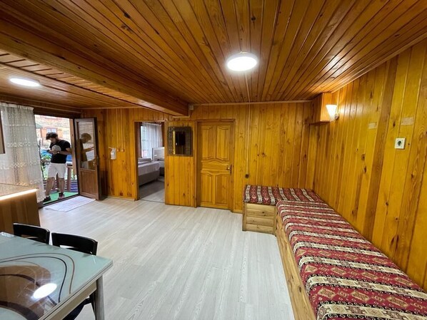 A wooden-paneled room with a bed, a table, and a bench.