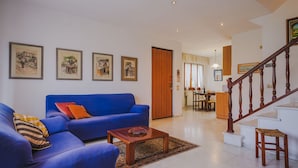 Ein Wohnzimmer mit einem blauen Sofa, einem Holztisch und einer Treppe.
