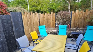 An outdoor patio with a yellow table and blue and gray chairs. - Groix Island Bed and Breakfast (BELZ)