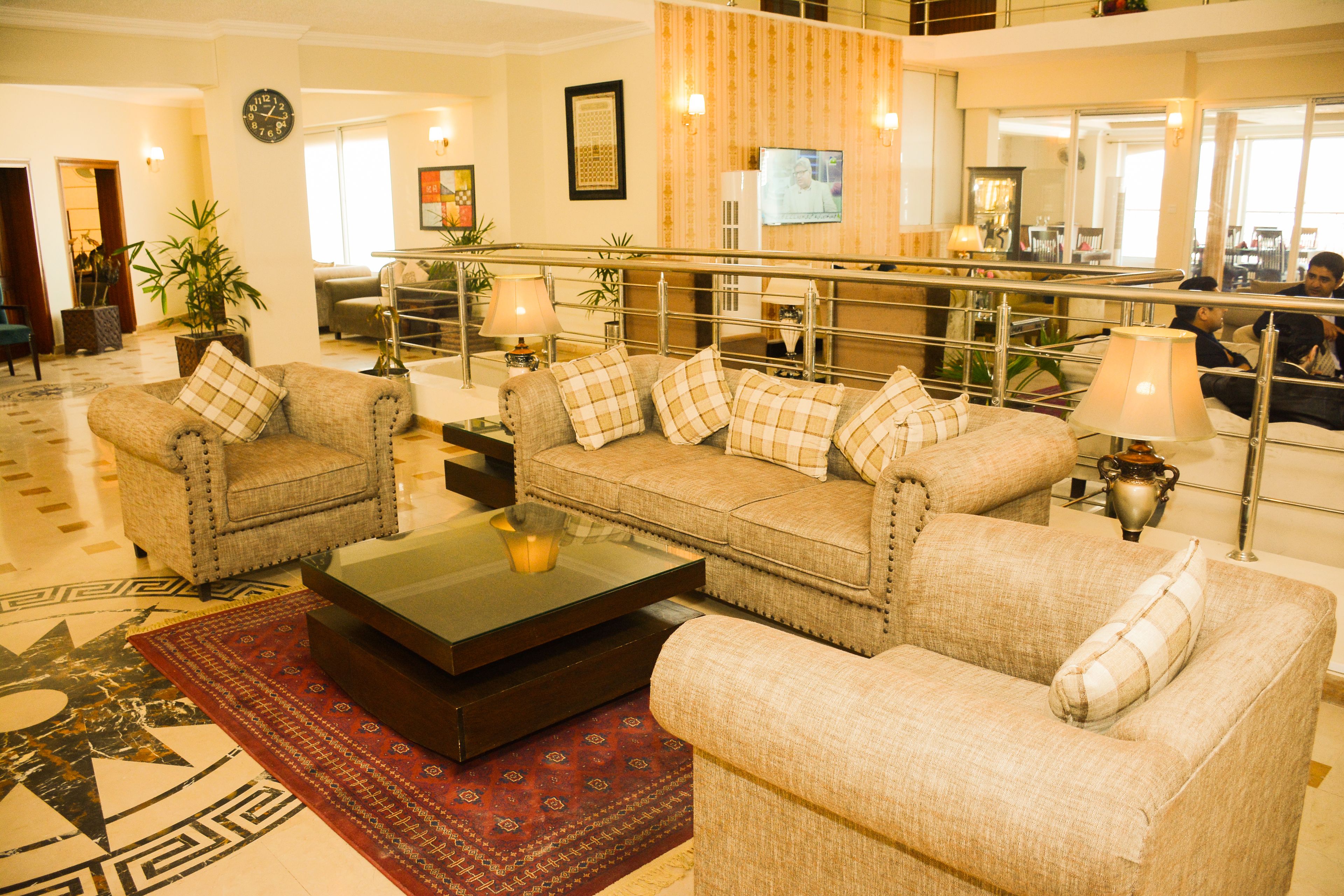 A spacious lobby with a modern design, featuring a large sofa set, a coffee table, and a decorative rug.