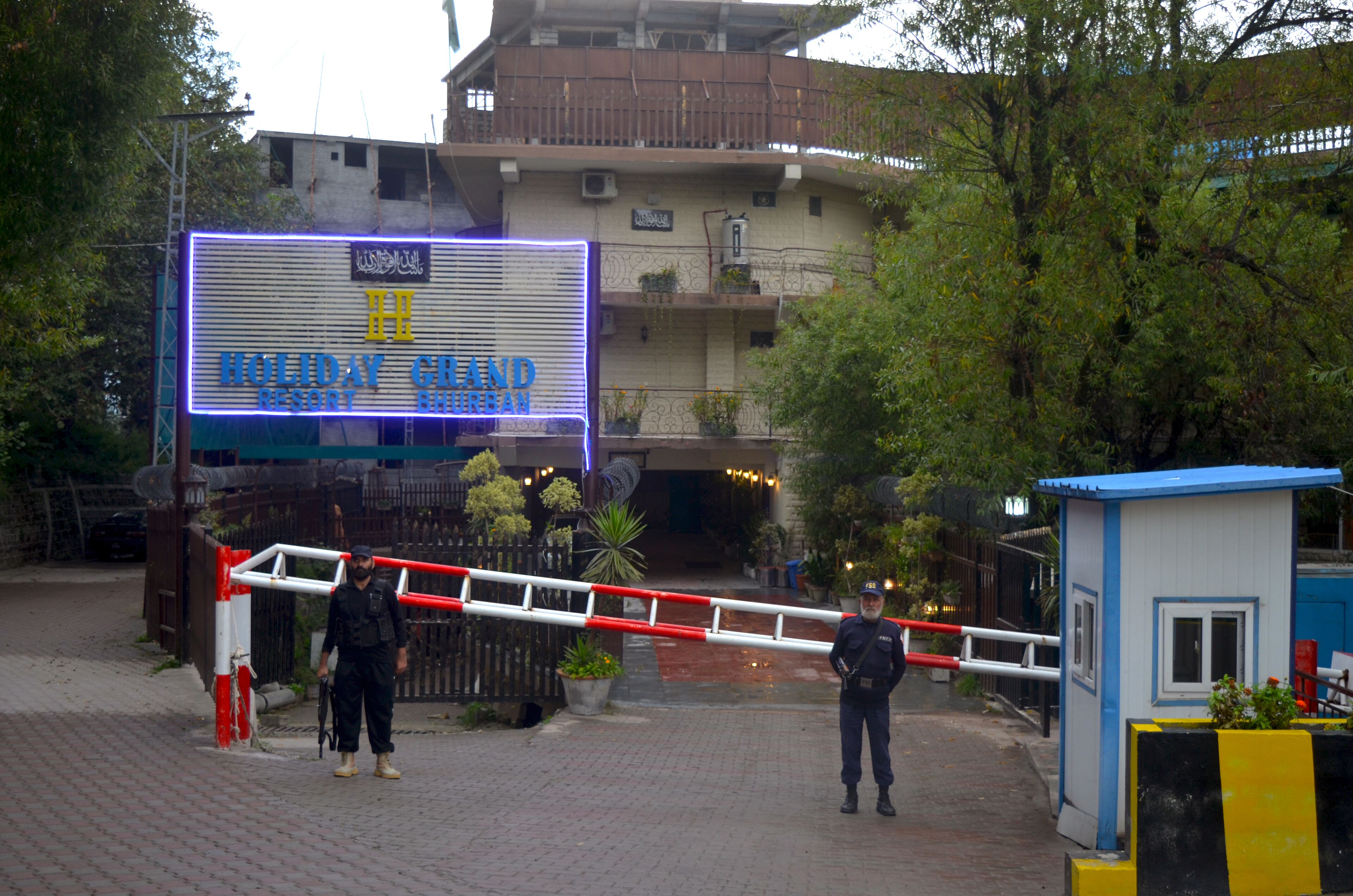 A gated entrance to a Holiday Inn Resort with a security guard present.