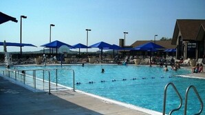 A swimming pool with multiple lanes, blue umbrellas, and lounge chairs. - 2BR 2BA + 3rd BR loft cozy end unit lakefront townhome comfortably sleeps 6! (Galena)