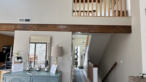A spacious loft with a high ceiling, exposed wooden beams, a central staircase, and a view to the upper floor. - 2BR 2BA + 3rd BR loft cozy end unit lakefront townhome comfortably sleeps 6! (Galena)
