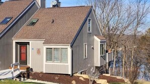 A modern two-story house with a sloped roof, a red door, and a small front porch. - 2BR 2BA + 3rd BR loft cozy end unit lakefront townhome comfortably sleeps 6! (Galena)