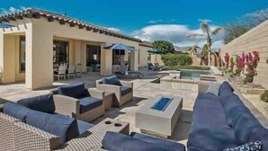 A poolside area with outdoor furniture, a pool, and a building with a tiled roof.