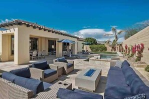 A poolside area with outdoor furniture, a pool, and a building with a tiled roof.