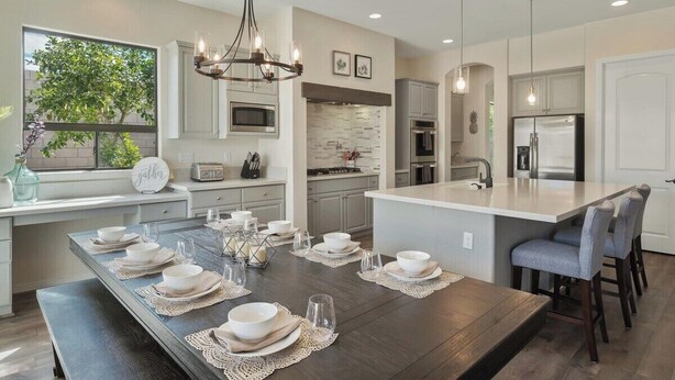 A modern kitchen with a large island, built-in appliances, and a dining area set for a meal.