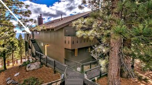 A multi-level building with a wooden exterior, surrounded by pine trees and a clear sky.